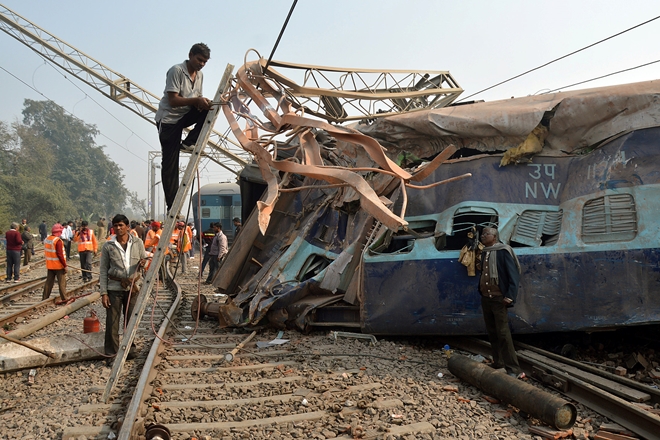 A man cuts an iron frame in front of a damaged coach of a passenger train after it derailed near Kanpur. (Reuters)
