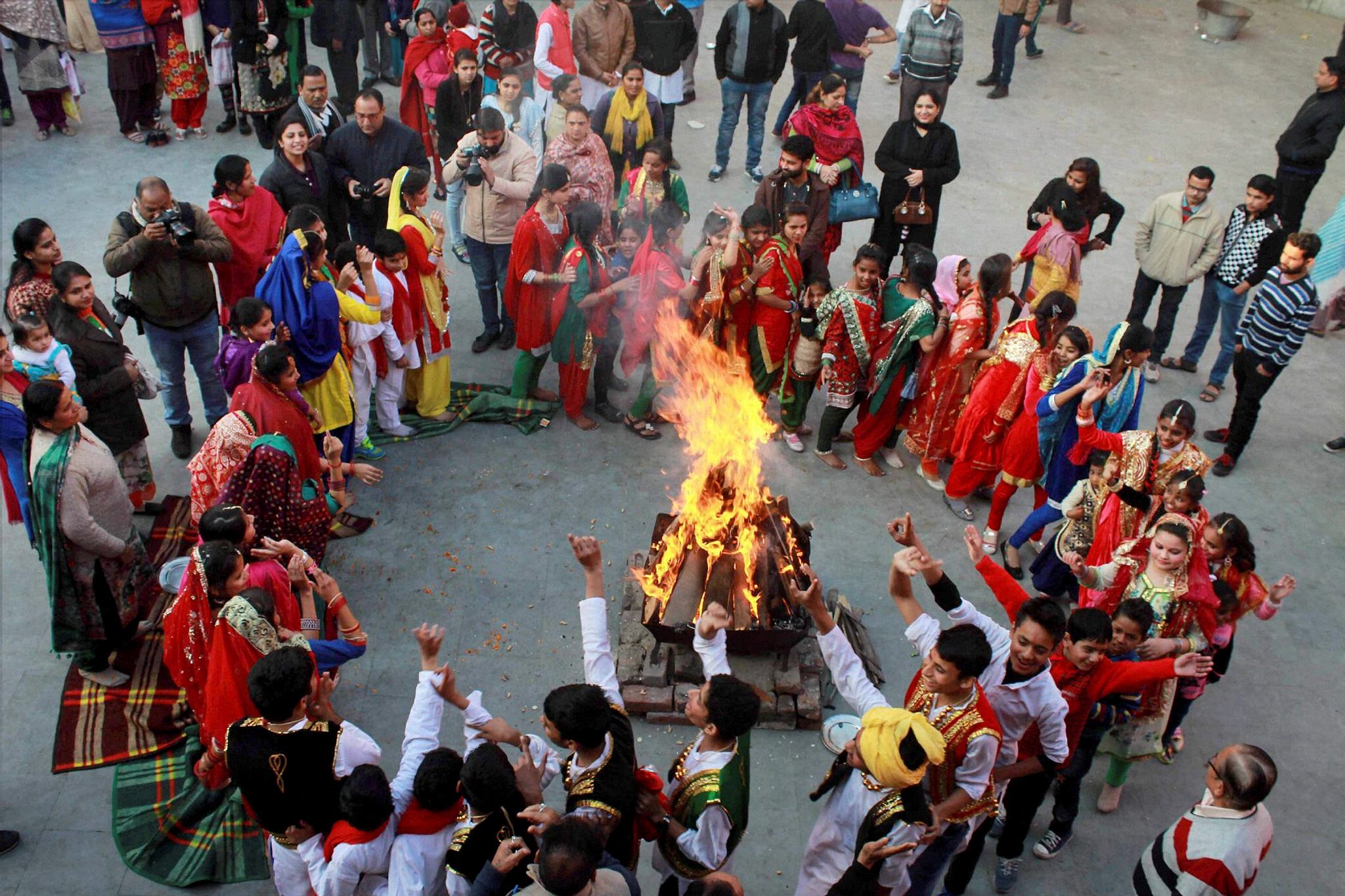 Girls in traditional attire dance around a bonfire as they celebrate Lohri festival in Jammu on Friday. (PTI)